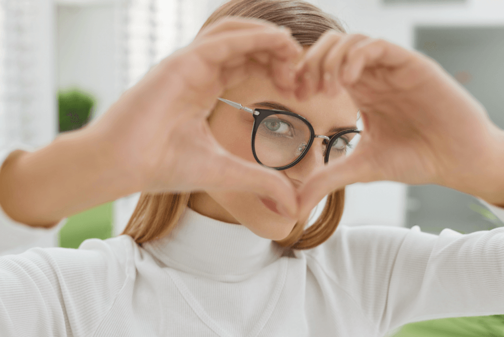 Femme avec des lunettes formant un cœur avec ses mains – image illustrant les mentions légales du site Optik Plérin